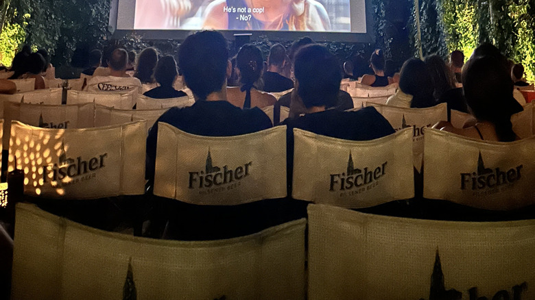 Outdoor cinema in a courtyard with trees and an apartment surrounding the screen