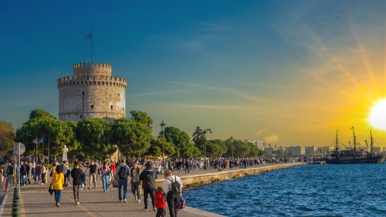 Busy boardwalk with the White Tower in the background a bright sunset over the water
