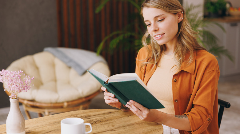 young happy woman reading a novel at coffee shop
