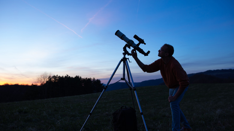 man with telescope at sunset