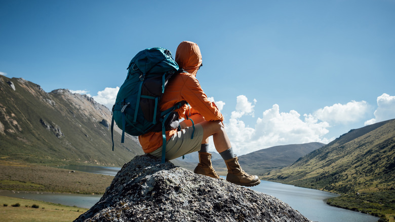 A man sitting on a rock with a backpack.