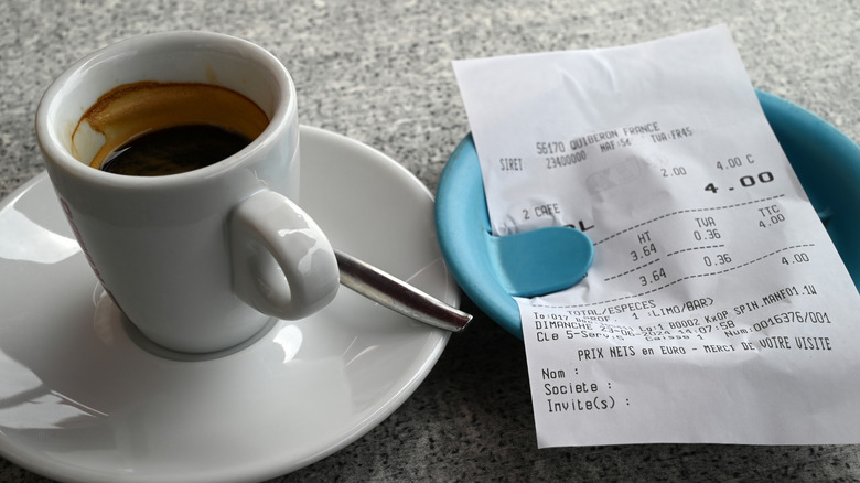 a cup of coffee and a receipt on a small dish