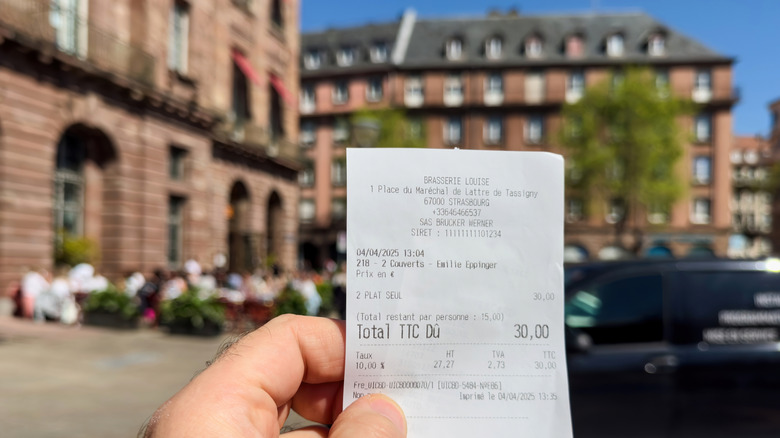 A hand holding a printed receipt in France
