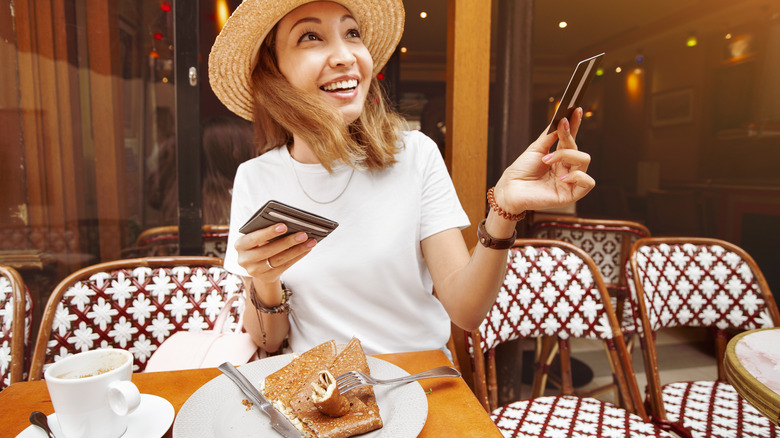 A woman is paying for a meal at a French café