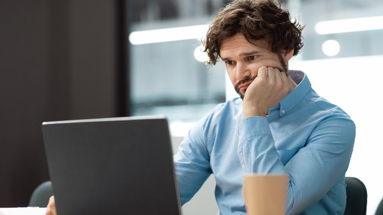 Confused man looking at laptop