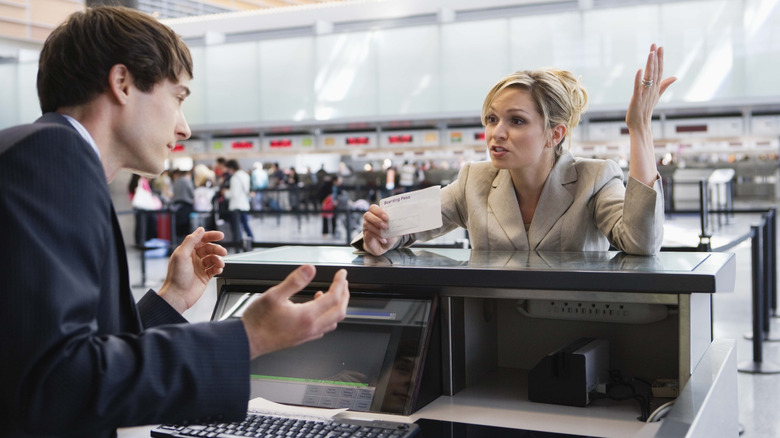 Frustrated traveler talking to ticket agent at airport