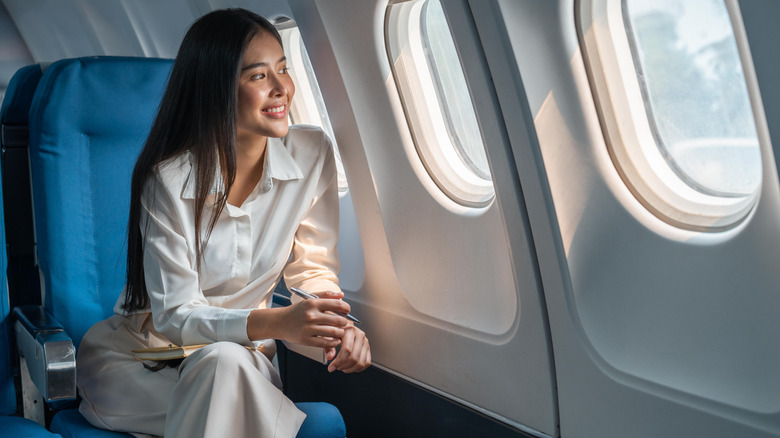 Cheerful woman sits near airplane window