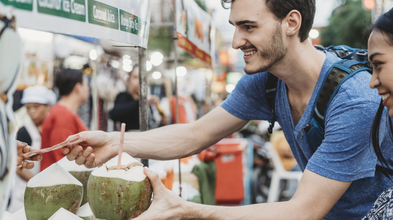 Travelers buying a coconut drink