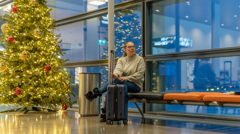 Airport traveler sitting by Christmas tree