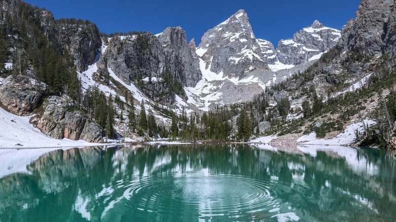 Calm lake by snowcapped mountains