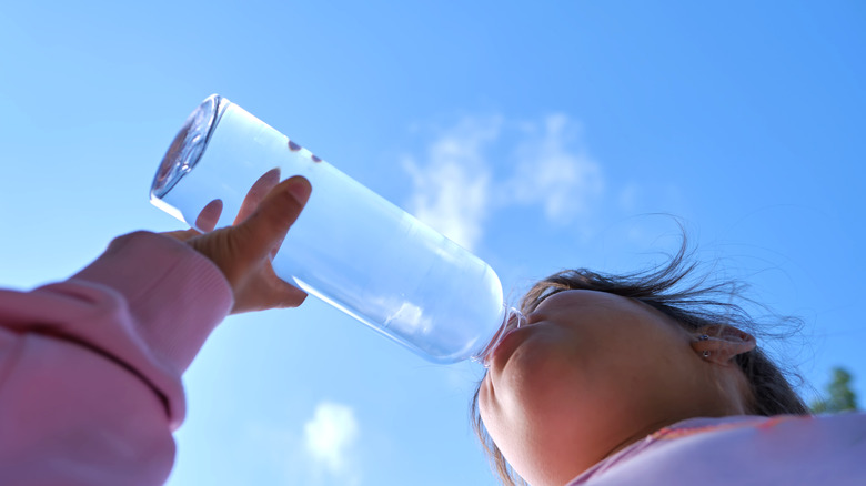 Girl drinks clean water from a transparent water bottle