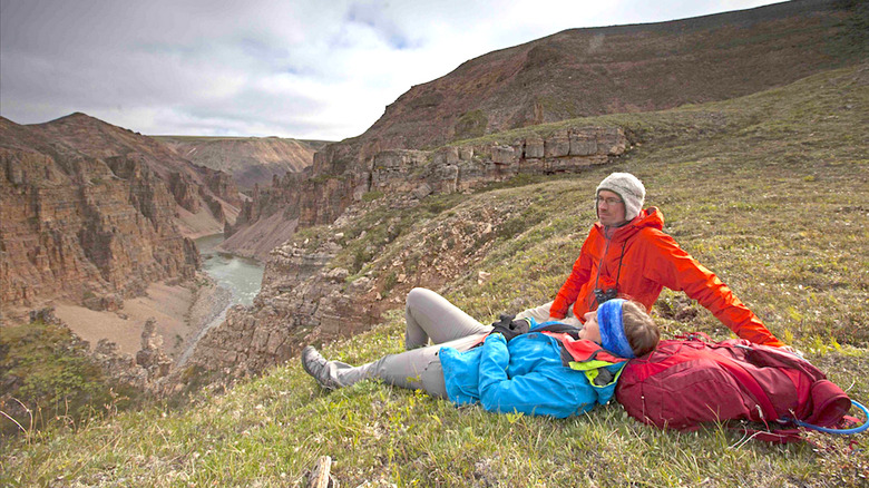 Backpackers lying on the edge of a canyon in Tuktut Nogait National Park.
