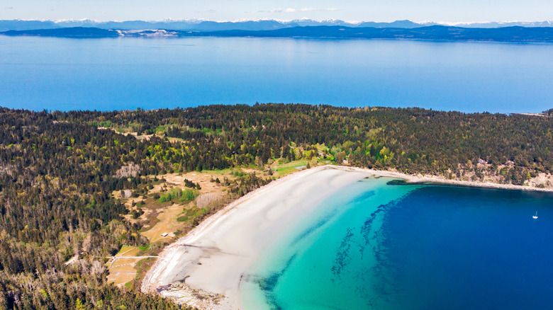 Aerial view of Tribune Bay with white sand beaches, turquoise ocean water and mountains