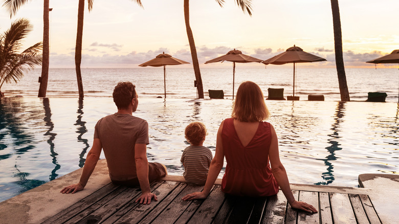 A family sitting on a resort dock, looking out at the water.