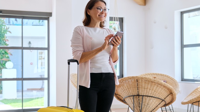 woman holding phone with luggage