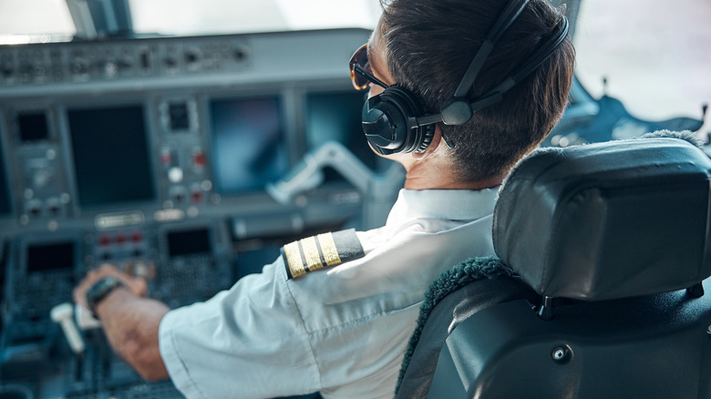 Pilot in cockpit holding airplane controls