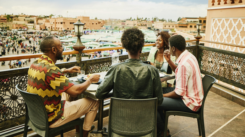 A group of friends sitting on a rooftop enjoying a meal together