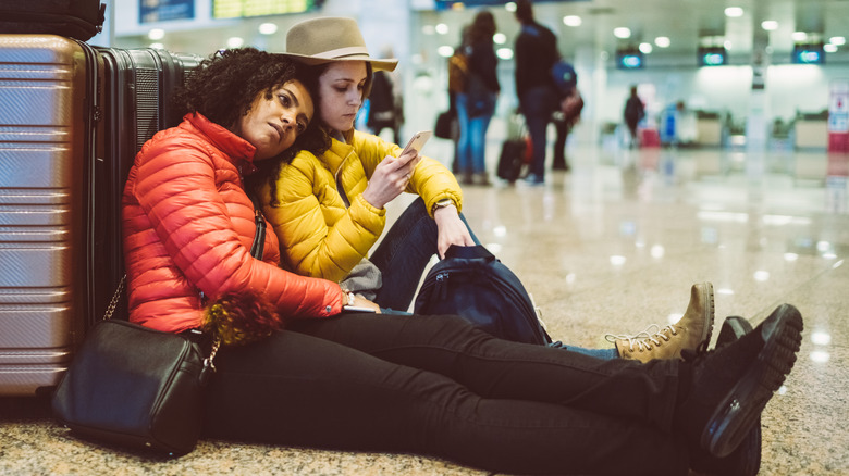 Two unhappy people sitting at the airport with luggage