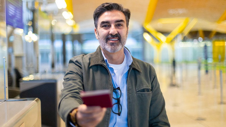 A happy man presents his red EU passport.