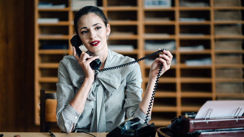 A woman on a landline telephone in an office.