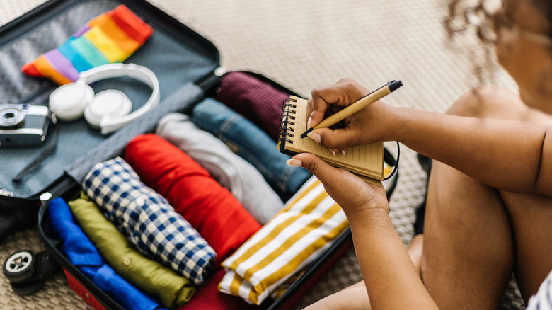 Woman taking notes while packing suitcase