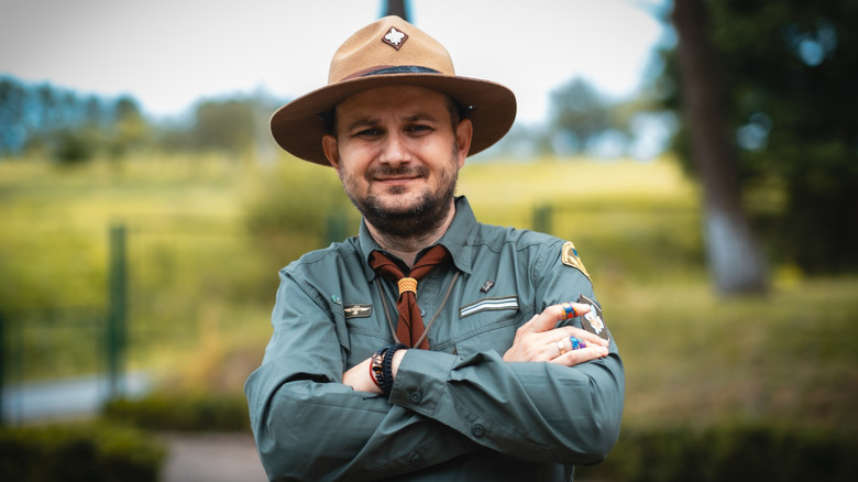 A park ranger grimaces with folded arms