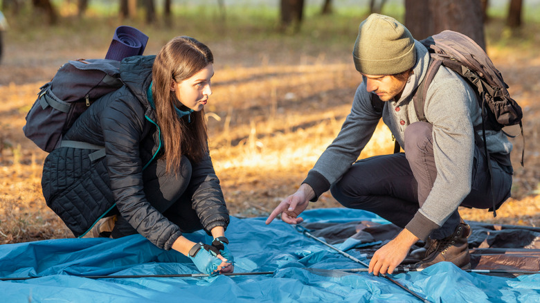 Two people repairing a tent