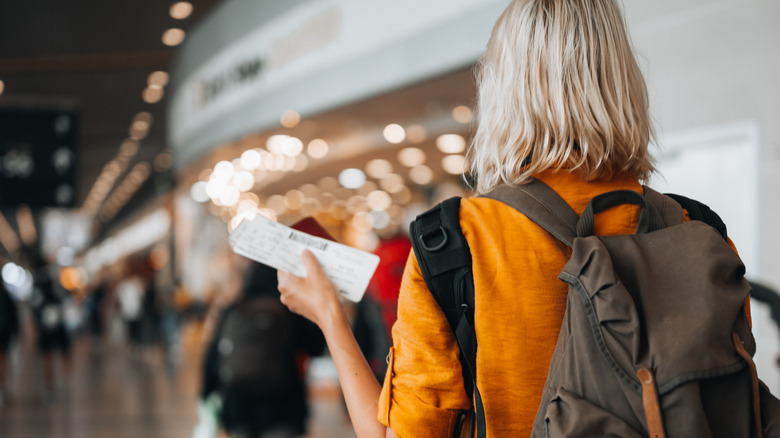 blonde woman holding airplane ticket