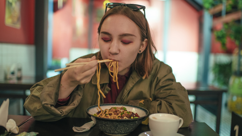 Woman eating noodles in restaurant