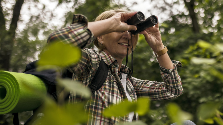 Hiker looking through binoculars smiling