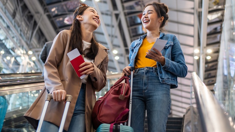 women with luggage on an escalator