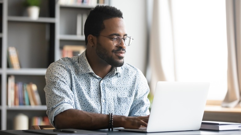 smiling man writing at laptop