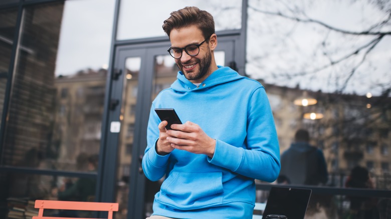 smiling man sitting outside on phone