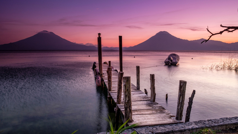A dock on Lake Atitlan and nearby volcanoes at sunrise