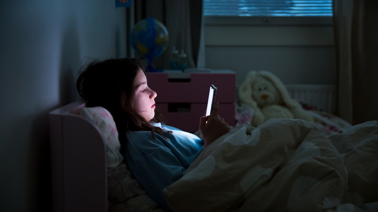 A child using a phone in bed in the dark