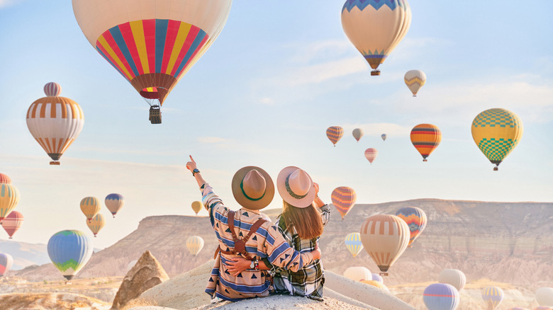 A happy traveling couple enjoying the view of hot air balloons
