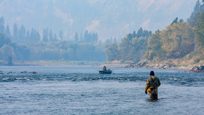A person in a boat and another fly fishing in the Clearwater River, Orofino, Idaho