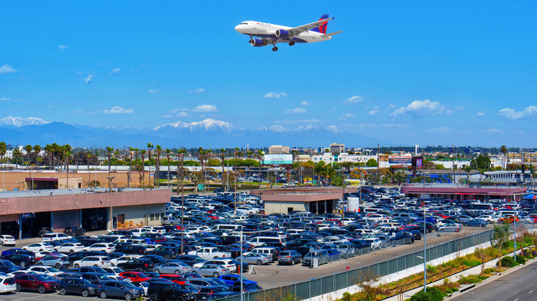 An airplane flies over the LAX budget parking lot.