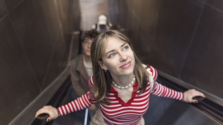 A young woman riding an escalator.