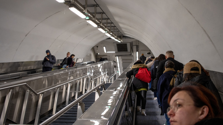 People riding an escalator in a tunnel.