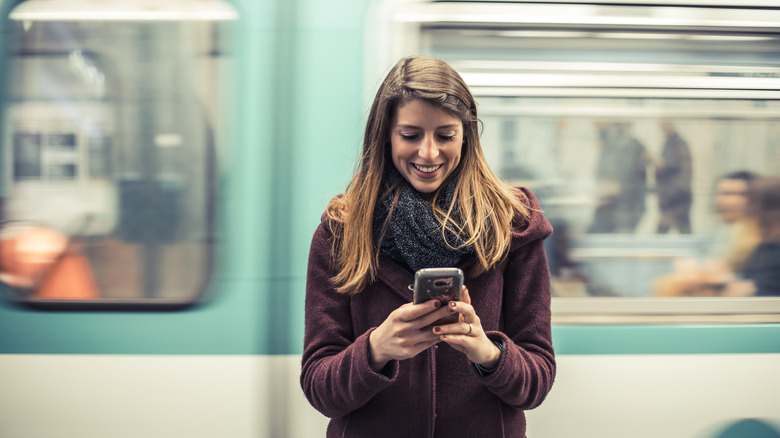 Woman looking at her phone in the Metro in Paris