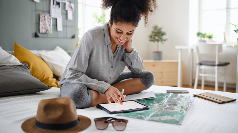 woman planning trip on bed