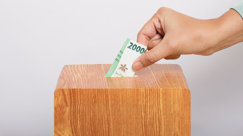 hand puts money into box