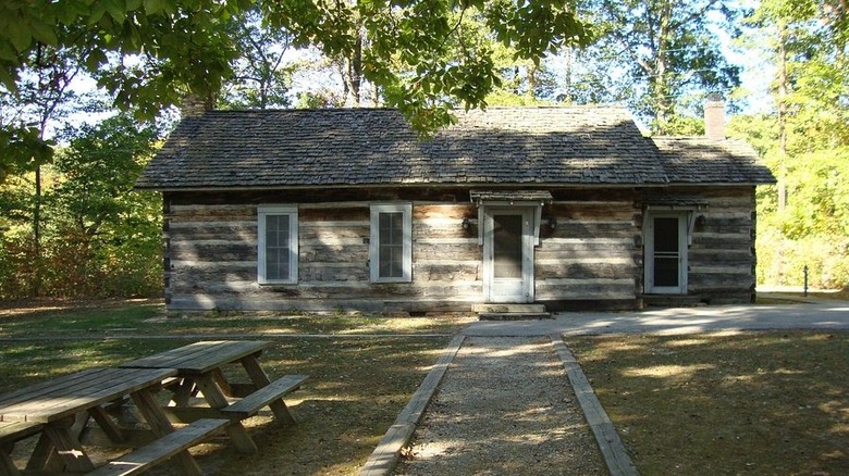 The log cabin recreational building at Shakamak state park with picnic tables out front.