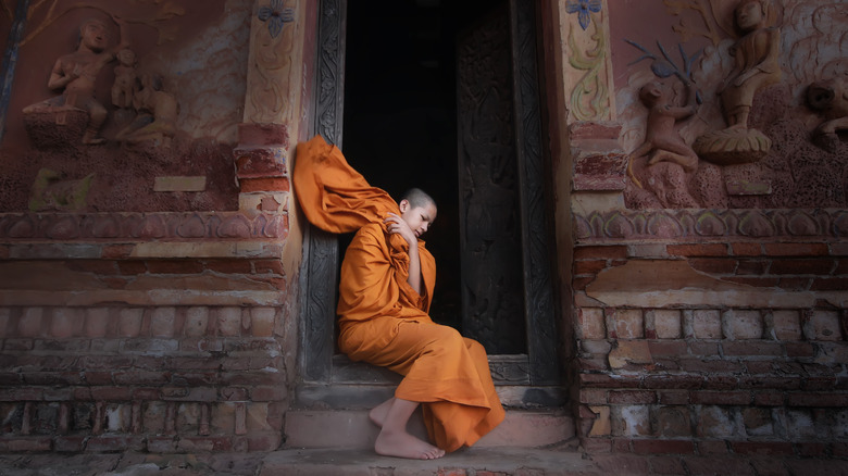 A novice monk adjusts his robe at an ancient temple