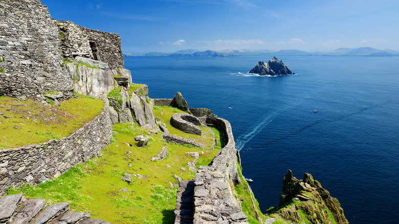 Ruins of a monastery on Skellig Michael island with rocky island in blue sea in the background