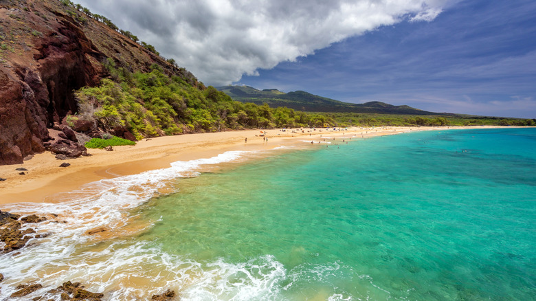 A beach in Maui with turquoise water and green cliffs