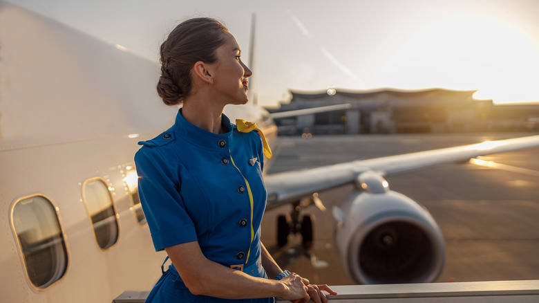 Flight attendant standing outside airplane