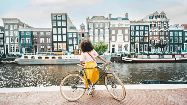 A woman with a bike enjoying the view of canal houses in Amsterdam