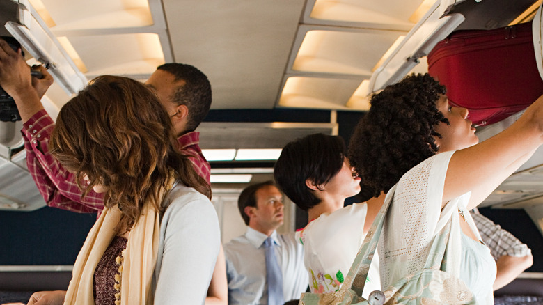 airline passengers using overhead compartments